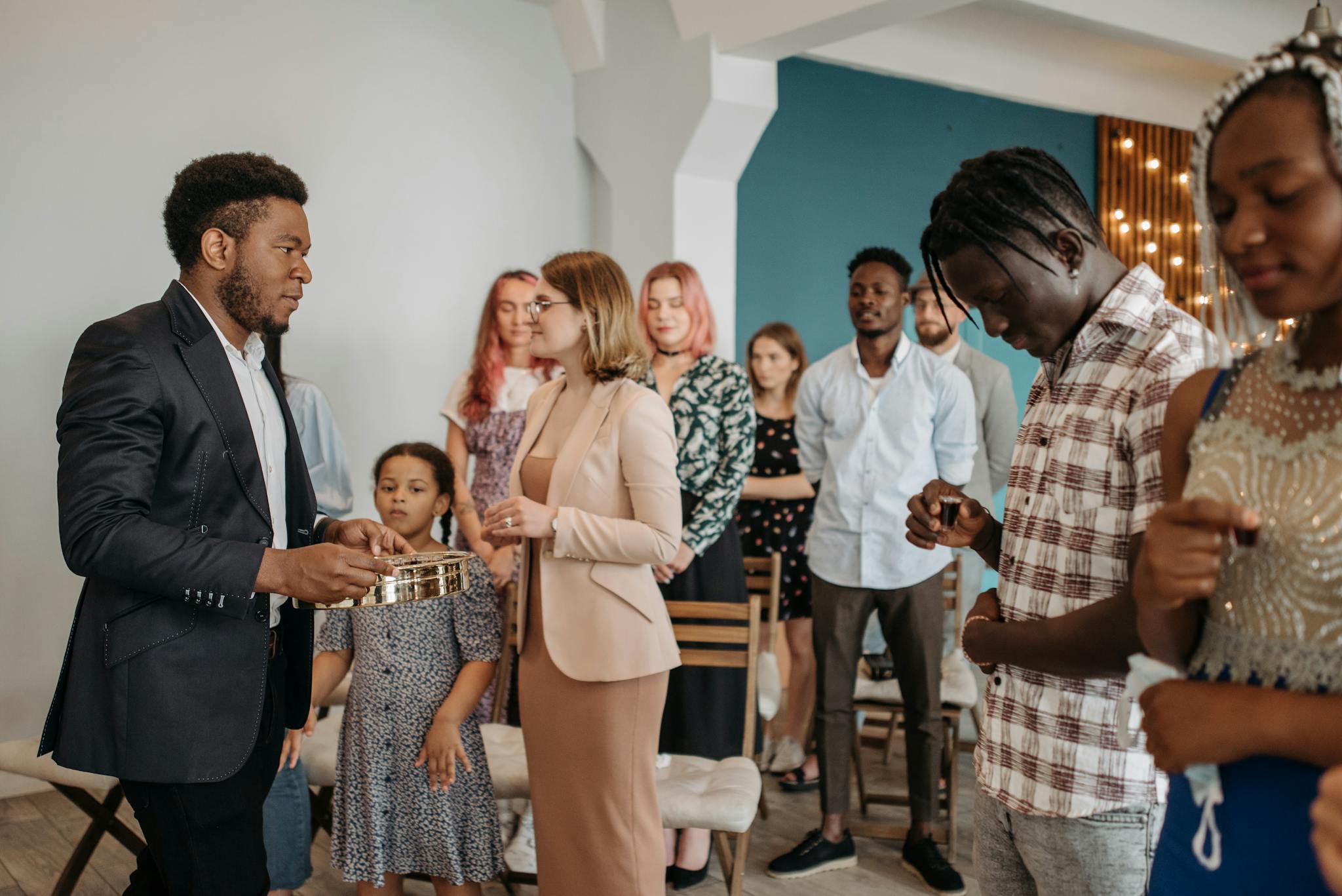 A diverse group of people standing in a church setting, participating in a religious ceremony.