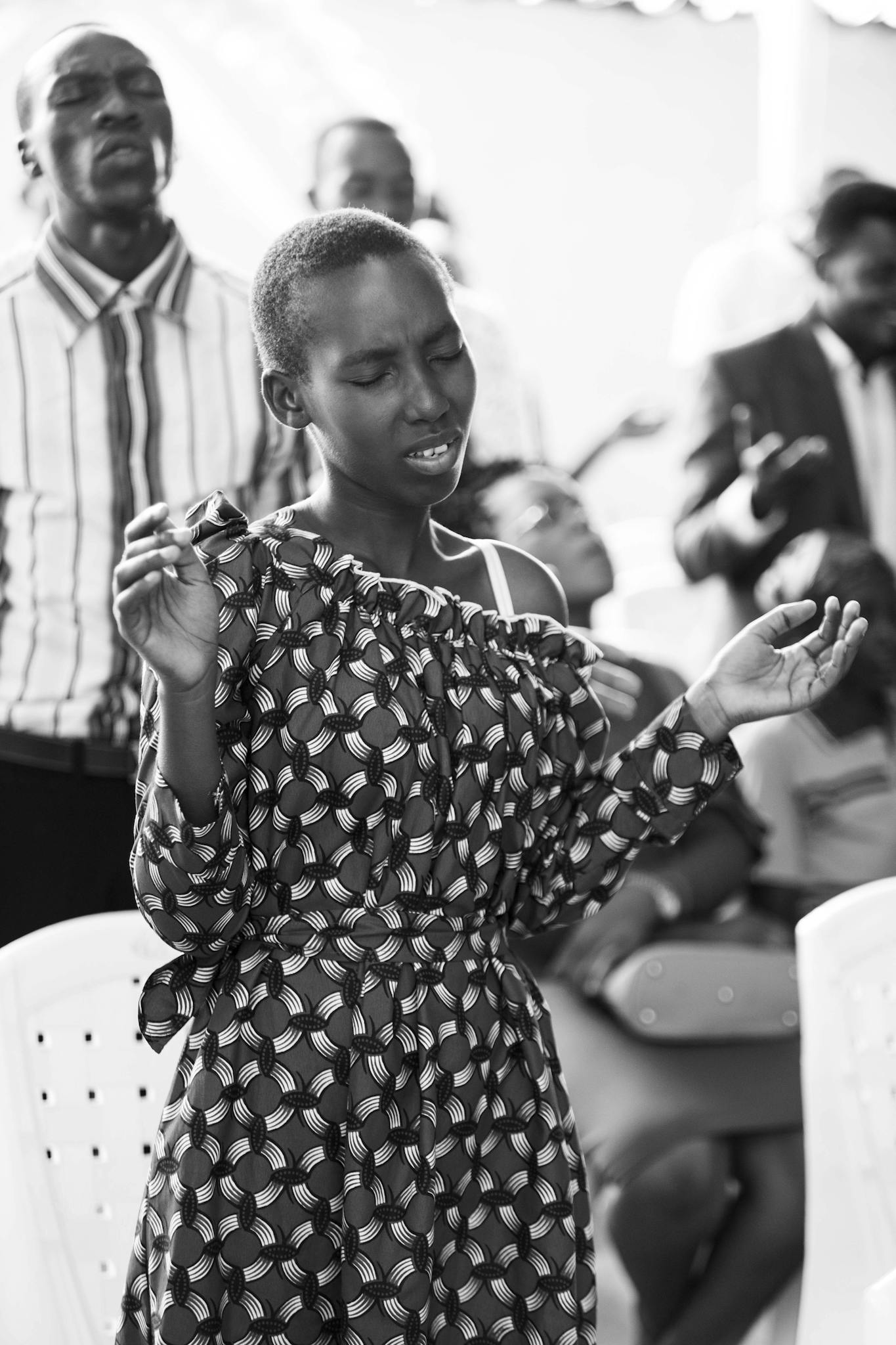 Group of diverse adults passionately singing and praying in a spiritual gathering.