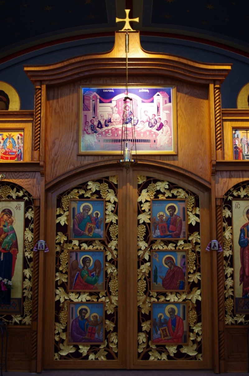 Carved wooden Holy Doors painted with the Annunciation and the four Evangelists, beneath an icon of the Mystical Supper