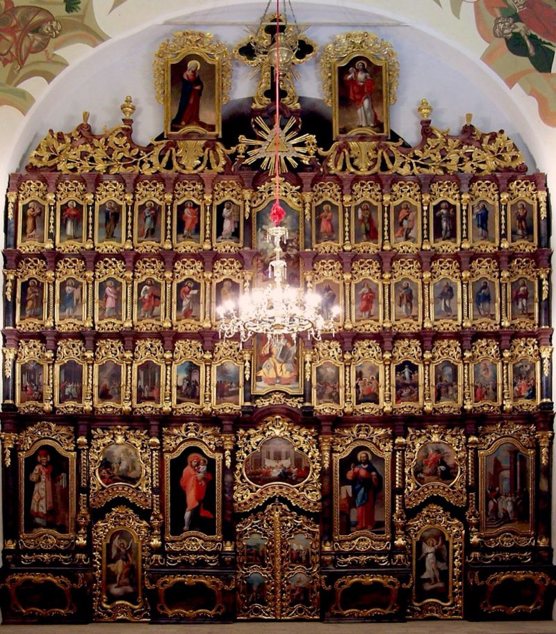 A gilded iconostasis of five tiers of painted icons, with the Holy Doors at its centre